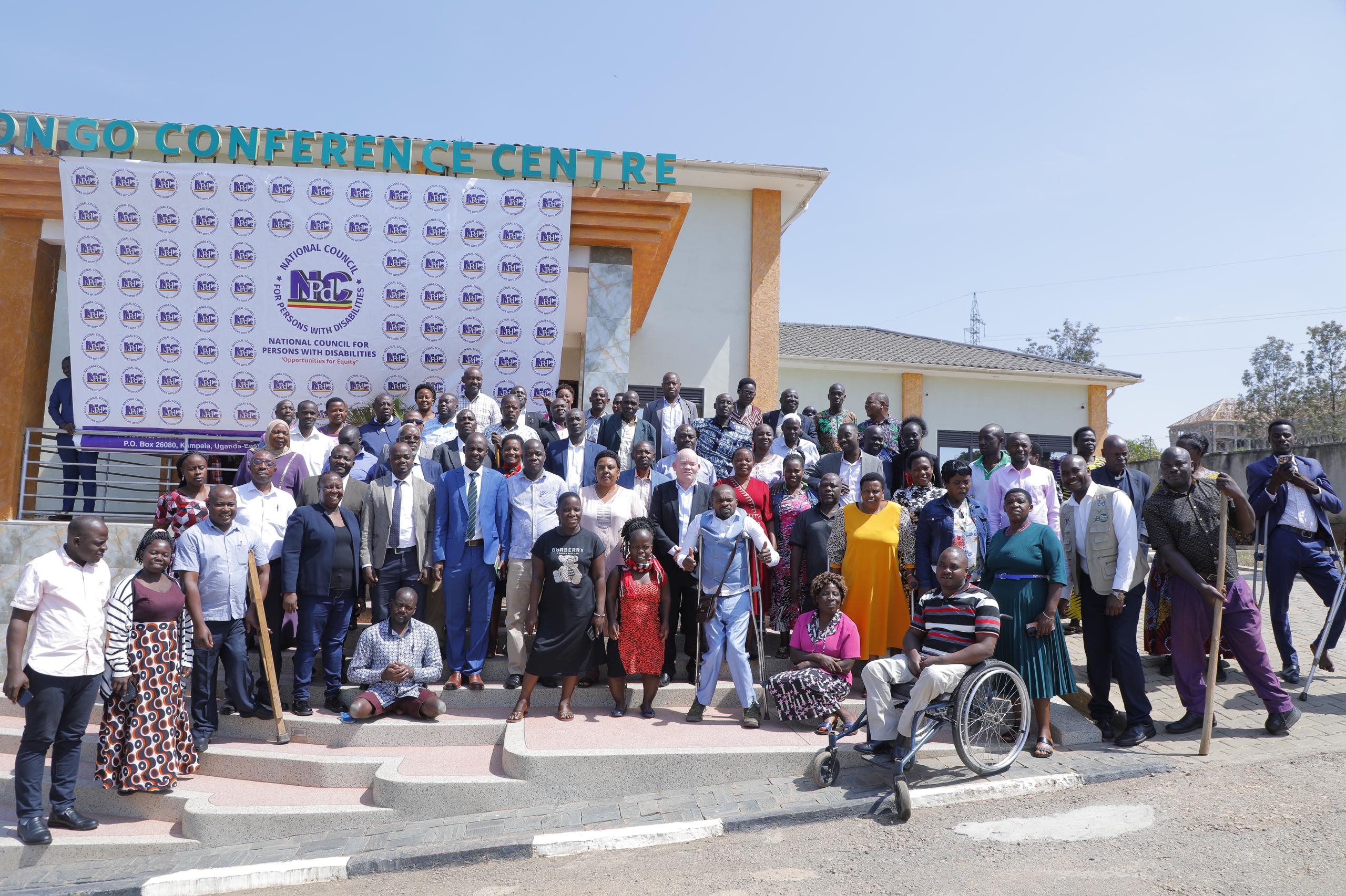 A group photo of persons with and without disabilities standing on steps of a hotel